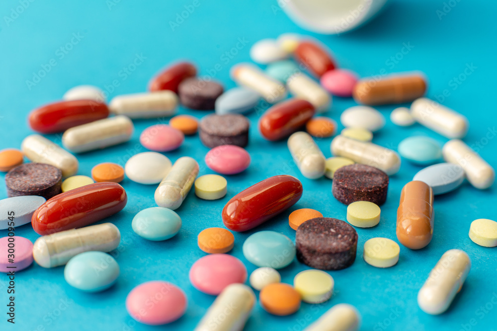 A scattered handful of colored pills on a blue background. Medical concept A scattered handful of colored pills on a blue background. Medical concept