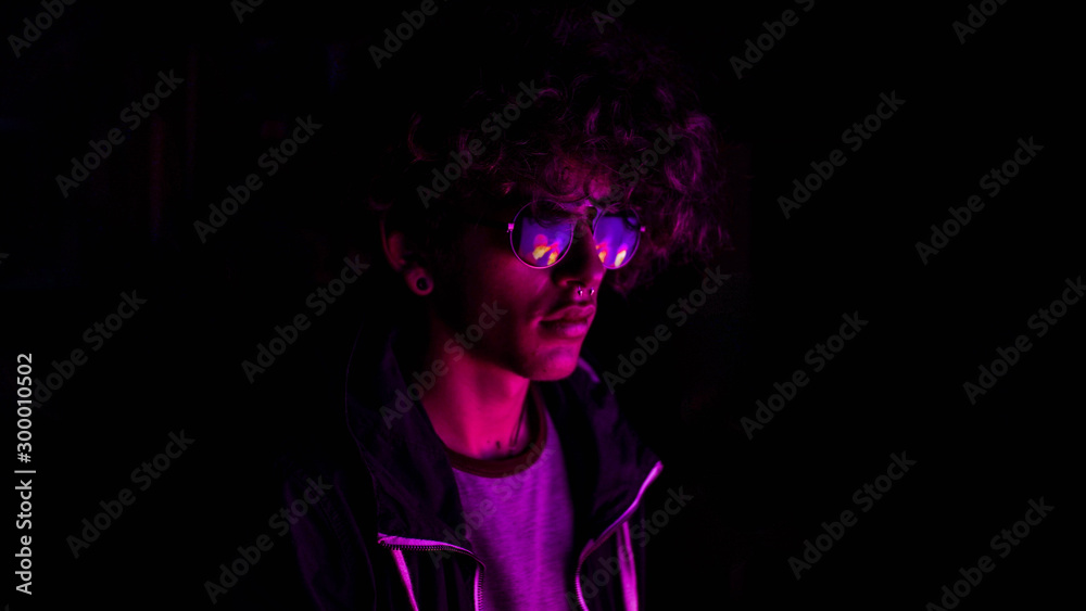 Fototapeta premium portrait of man with neon colors and in his lenses the reflection of a neon light purple color