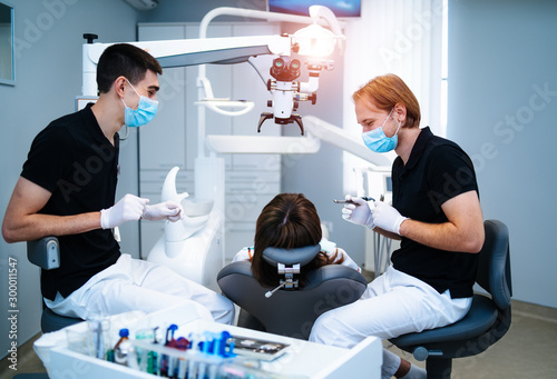 Two dentists examine the patient's teeth for the further treatment. Modern stomatology cabinet.