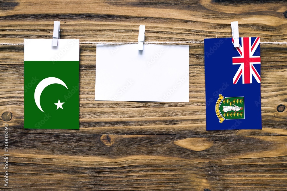 Hanging flags of Pakistan and British Virgin Islands attached to rope with clothes pins with copy space on white note paper on wooden background.Diplomatic relations between countries. Hanging flags of Pakistan and British Virgin Islands attached to rope with clothes pins with copy space on white note paper on wooden background.Diplomatic relations between countries.