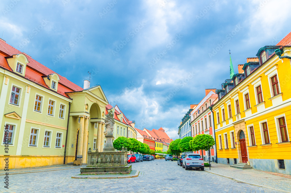 Cobblestone street with colorful buildings and Statue of Madonna and Child monument with blue cloudy sky background in old historical city centre, Ostrow Tumski, Wroclaw, Poland