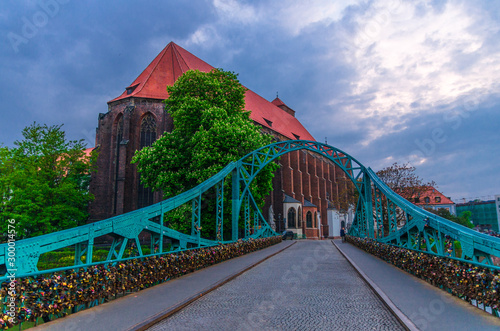 Roman Catholic parish Saint Mary church NMP on Sand island Wyspa Piasek, view through arch of Tumski bridge over Odra Oder river in old town historical city centre of Wroclaw, evening view, Poland