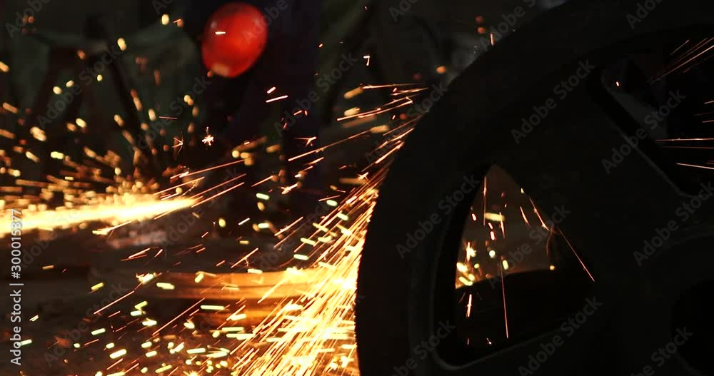 Male hand cuts off pieces of water pipe with angle grinder. Cutting of a steel with splashes of sparks at construction site. Sparks during cutting of metal angle grinder