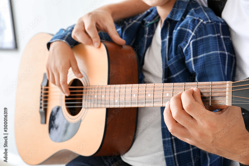 Man teaching his little son to play guitar, closeup