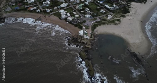 Aerial top scene of lighthouse at sandy shore. Changing to front panoramic view of touristic town at pensinsula at sunset. Jose Ignacio lagoon at background. Uruguay, Maldonado photo