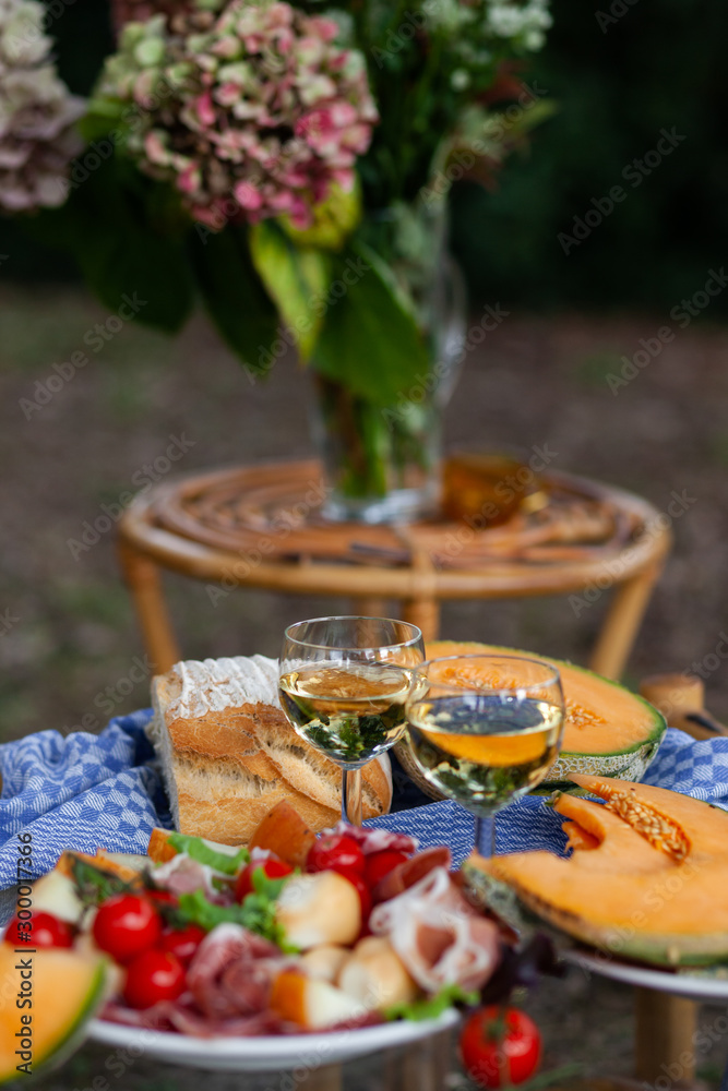 Delicious snacks for romantic dinner for a couple. Wine, fruits, light food. Beautiful table decor, bright colors. Outside, closeup