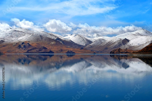The Yamdrok Lake, reflecting the brown colors of Mt. Naiqinkangsang against a blue clear sky.