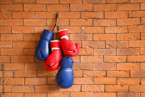 Boxing gloves hanging on brick wall © Pixel-Shot