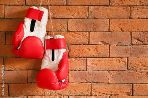 Boxing gloves hanging on brick wall © Pixel-Shot
