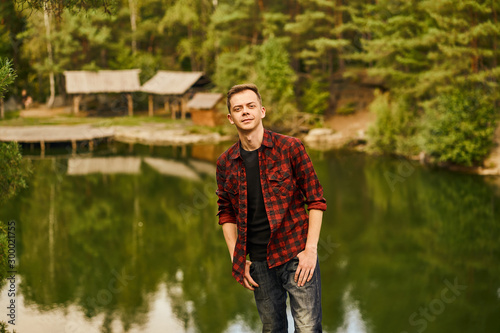 Male tourist exploring new places. Portrait of handsome man on nature near the lake at forest background. © IC Production
