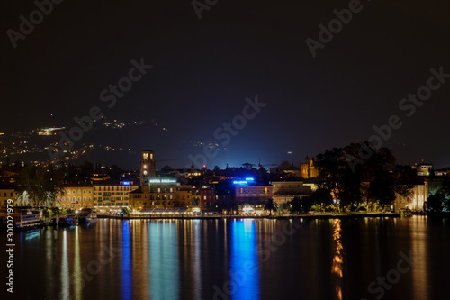 Evening panoramic view of the center of Riva Del Garda, Lake Garda. City night lights reflected in water