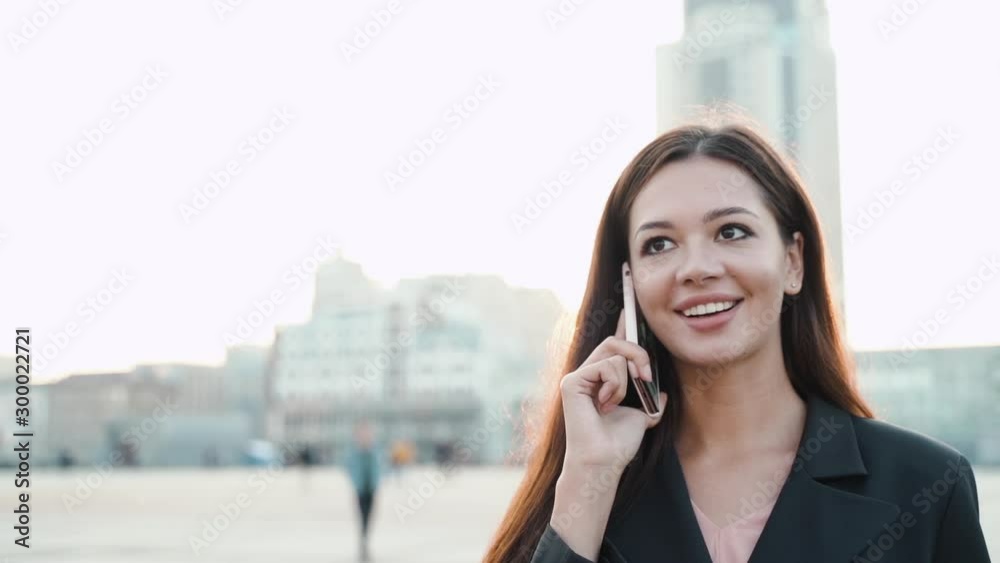 Young adult business lady talking on modern smartphone in city Young adult business lady talking on modern smartphone in city