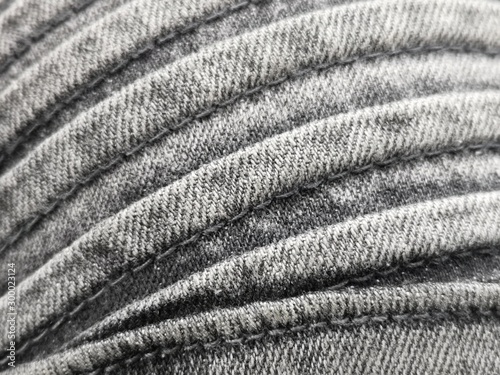 Reinforced detail of modern stylish clothes. Close-up photo of fashion featuring strongly stitched  structure of fabric. Curvilinear geonetric background of rough texture material with seams.
