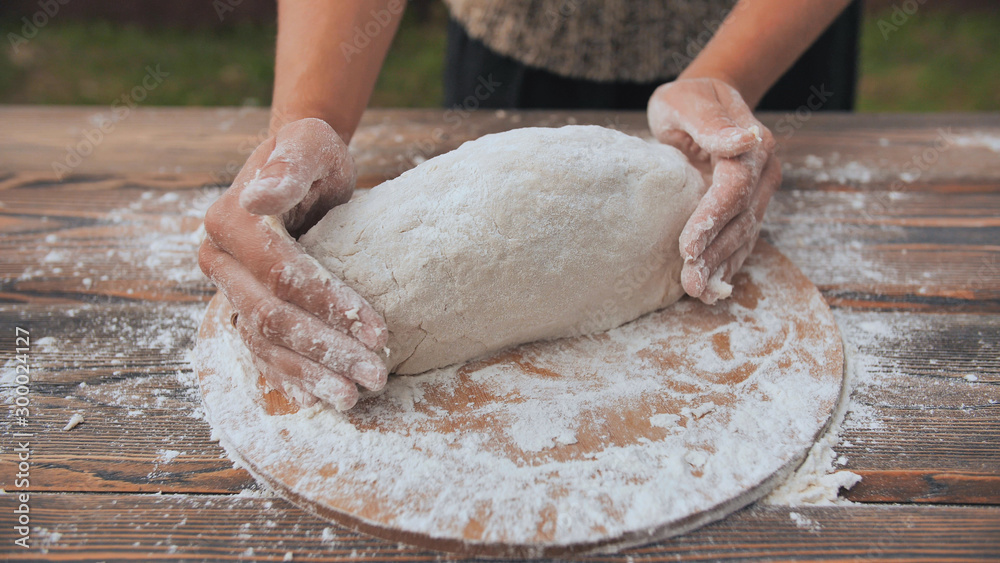 A young woman kneads the dough with her hands and puts it into the mold. Homemade bread baking. A young woman kneads the dough with her hands and puts it into the mold. Homemade bread baking.