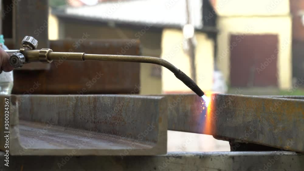 Cutting a steel profile with an acetylene torch. Worker gently heating a steel element with a cutting torch. Cutting a steel profile with an acetylene torch. Worker gently heating a steel element with a cutting torch.