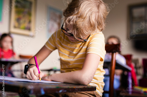 Blonde boy with glasses drawing. Group of elementary school pupils in classroom on art class. Russia, Krasnodar, May, 23, 2019