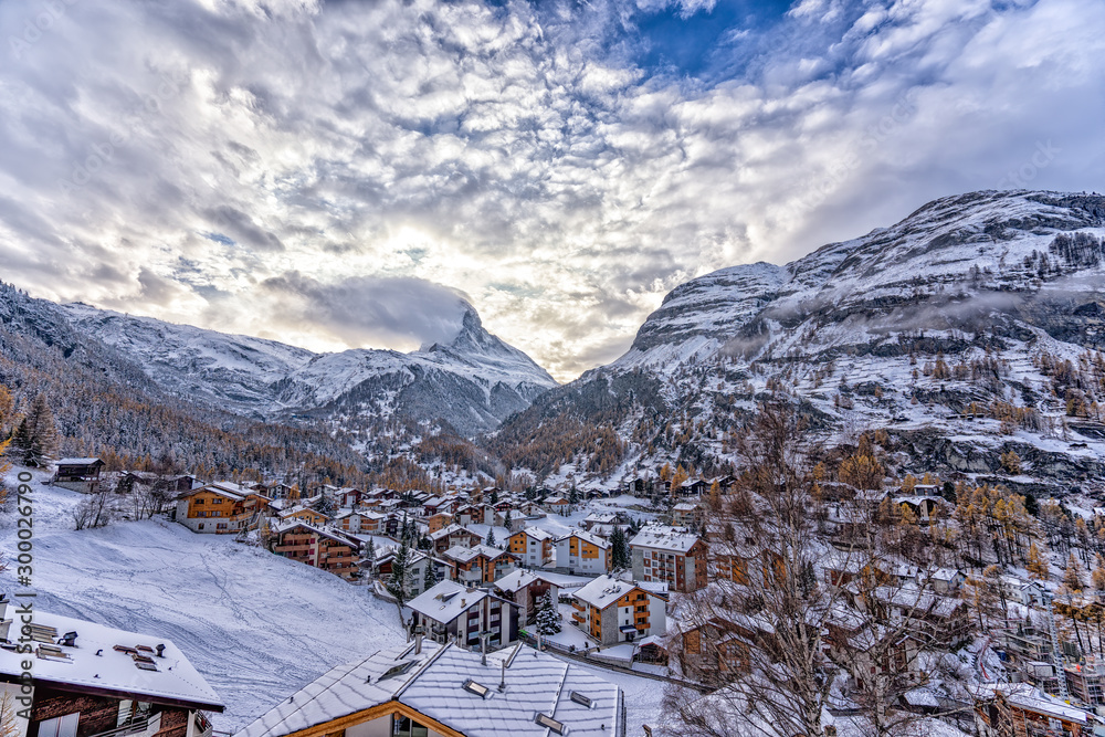 View of Matterhorn mountain with clouds and Swiss village in the foreground