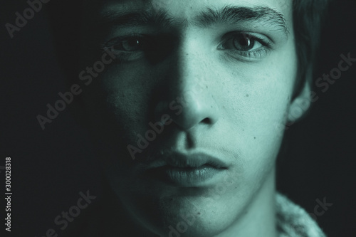 Portrait of a young man. Portrait of a handsome man, looking in the camera. Closeup face of a caucasian teenage boy. Confident and serious look of a teenager, at studio. Art style. Black and white.