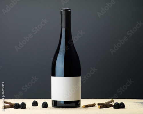 Bouteille vin rouge réglisse framboise sable fond gris sombre