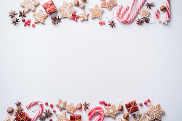 Winter holidays design greeting card. Festive sweets and decorations border on white surface. Christmas, New Year, seasonal concept. Copy space.