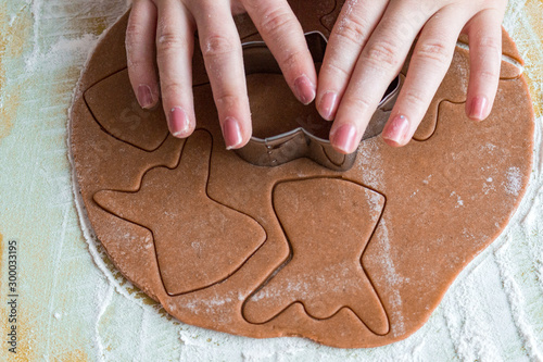 Woman's hands squeeze christmas shapes gingerbread cookie from the dough