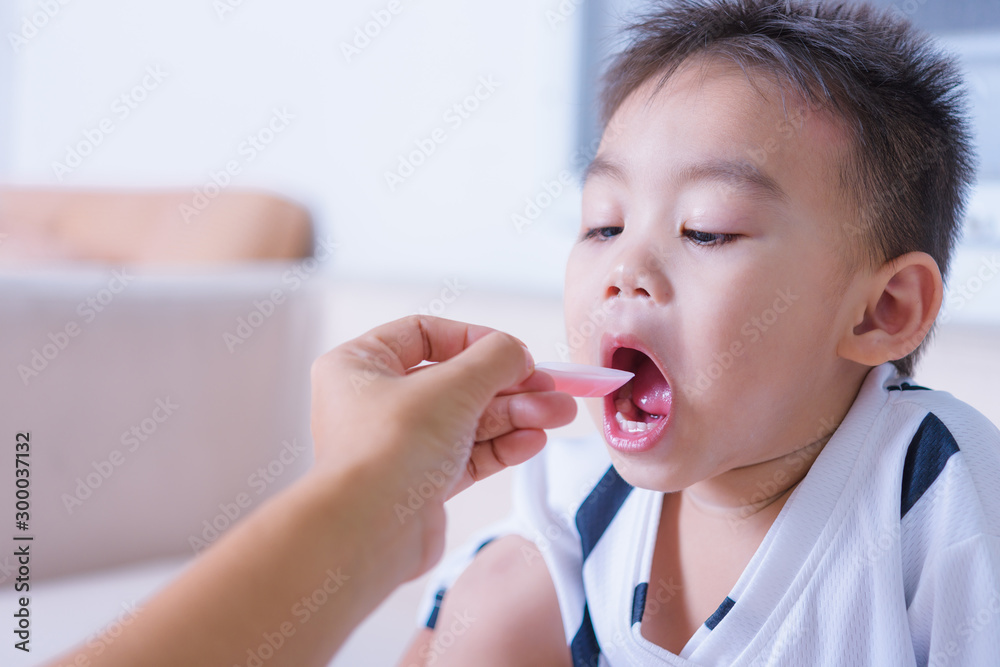 Asian children boy sick he take medicine by spoon Asian children boy sick he take medicine by spoon