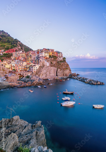 Long exposure shot of Manarola with Rock in the foreground in Cinque Terre, Italy during sunset hours