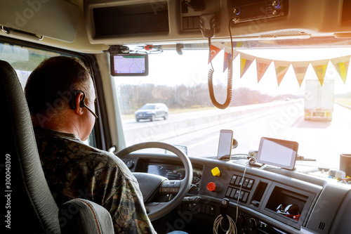 Driver in cabin of big modern truck photo