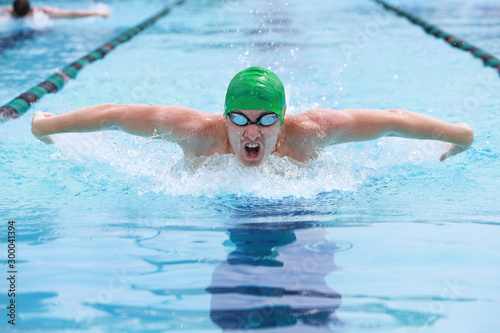 Teenage boy swimming butterfly stroke in a race