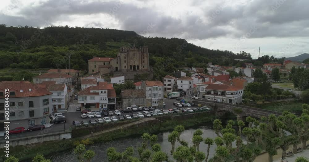 Aerial: Drone approaching vehicles by bridge over Sar River amidst buildings near Convento del carmen in town against cloudy sky - Padron, Spain Aerial: Drone approaching vehicles by bridge over Sar River amidst buildings near Convento del carmen in town against cloudy sky - Padron, Spain