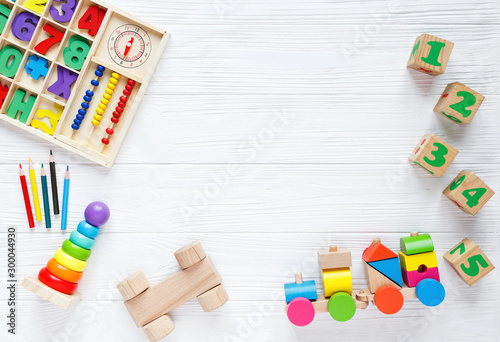 Kids toys: pyramid, wooden blocks, xylophone, train on white wooden background. Top view. Flat lay. Copy space for text