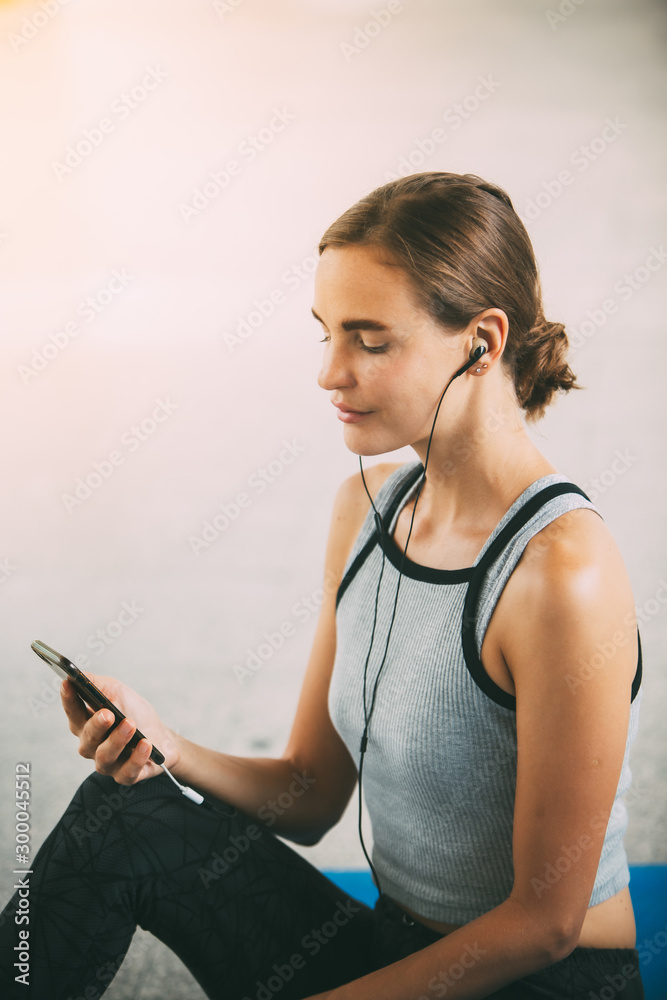 Portrait of fit and sporty young woman asian outdoors listening music using mobile phone. Fitness female looking relaxed in city Portrait of fit and sporty young woman asian outdoors listening music using mobile phone. Fitness female looking relaxed in city
