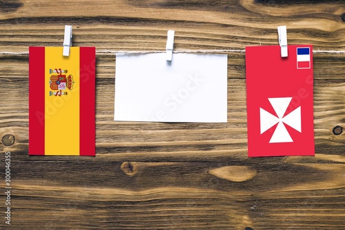Hanging flags of Spain and Wales, Galler, Welsh flag, galler flag attached to rope with clothes pins with copy space on white note paper on wooden background.Diplomatic relations between countries. photo