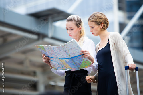 Travel and tourism concept. Two caucasian Woman traveler tourist walking with luggage and looking the map in the city