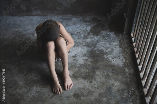 Foto child hug her knee on floor, while sitting alone in cage was imprisoned make no freedom,Violent action against children, Violence against children and human trafficking