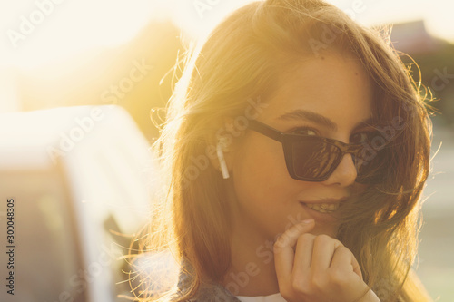 Dynamically young girl walks down the street. Hair fluttering in wind. Concept of street fashion. Young beautiful model in the city. Pretty woman listening music with wireless headphones in street photo