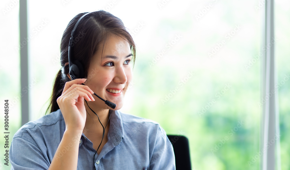 Attractive business woman Asian in suits and headsets are smiling while working with computer at office. Customer service assistant working in office Attractive business woman Asian in suits and headsets are smiling while working with computer at office. Customer service assistant working in office