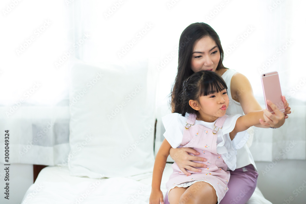 beautiful mother and her daughter making a selfie using smart phone and smiling beautiful mother and her daughter making a selfie using smart phone and smiling