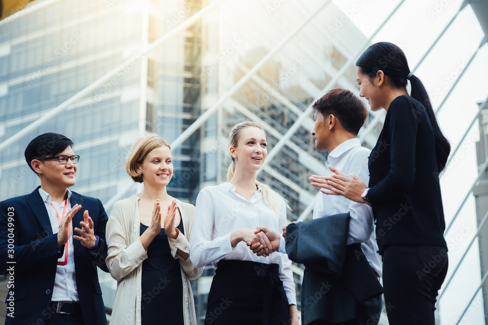 Business team celebrating and success concept.Two businessmen shaking hands with their colleagues applauding Business team celebrating and success concept.Two businessmen shaking hands with their colleagues applauding