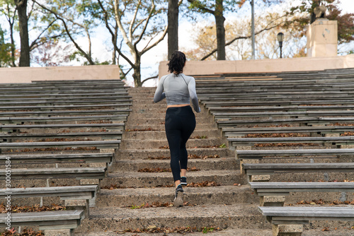 Back view of young woman running upstairs exercising 