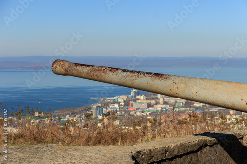 The barrel of the 130-mm gun B-13-3s located on the battery at the top of the Holodilnik hill, against the background of the panorama of the city of Vladivostok. © Сергей Рамильцев