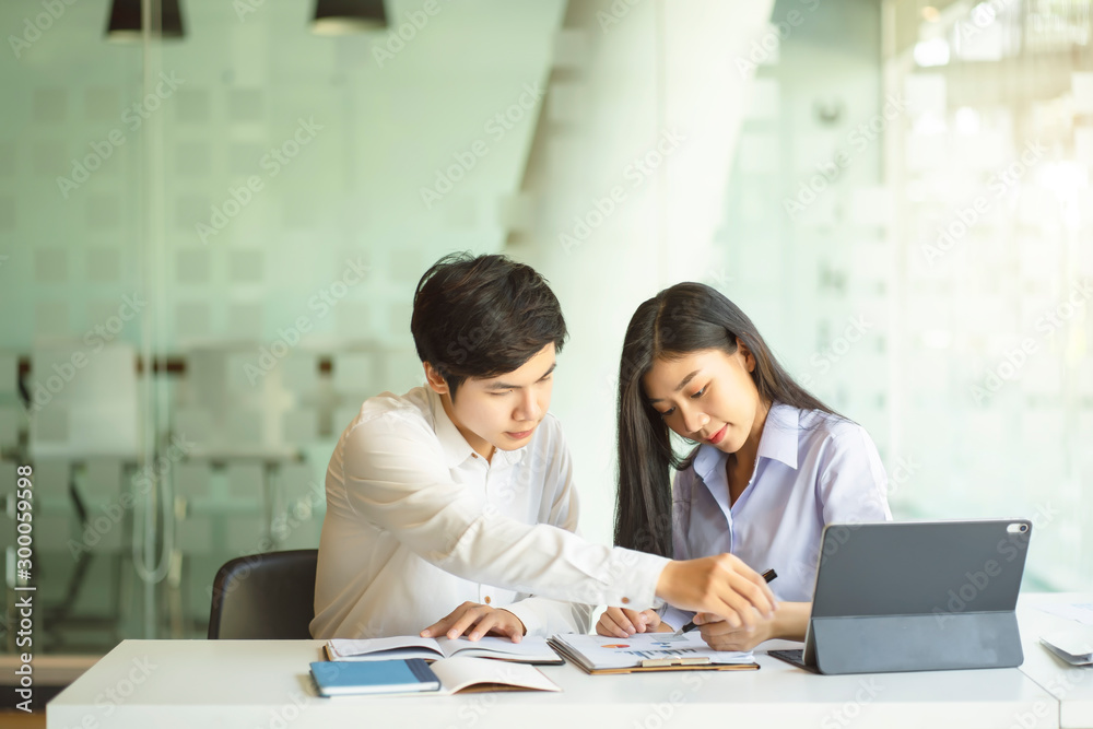 Young Asian couple or college student using digital tablet and laptop computer notebook work together at coffee shop or university campus. Young Asian couple or college student using digital tablet and laptop computer notebook work together at coffee shop or university campus.