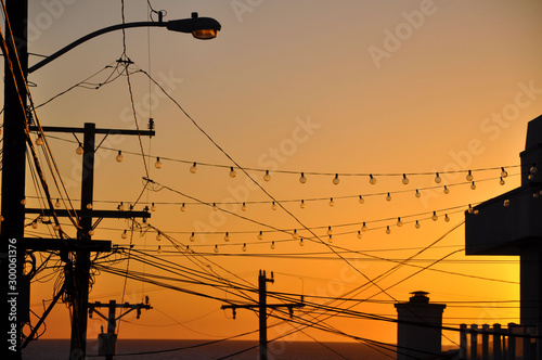 Silhouette of lights, street lamps, and wires at sunset sky