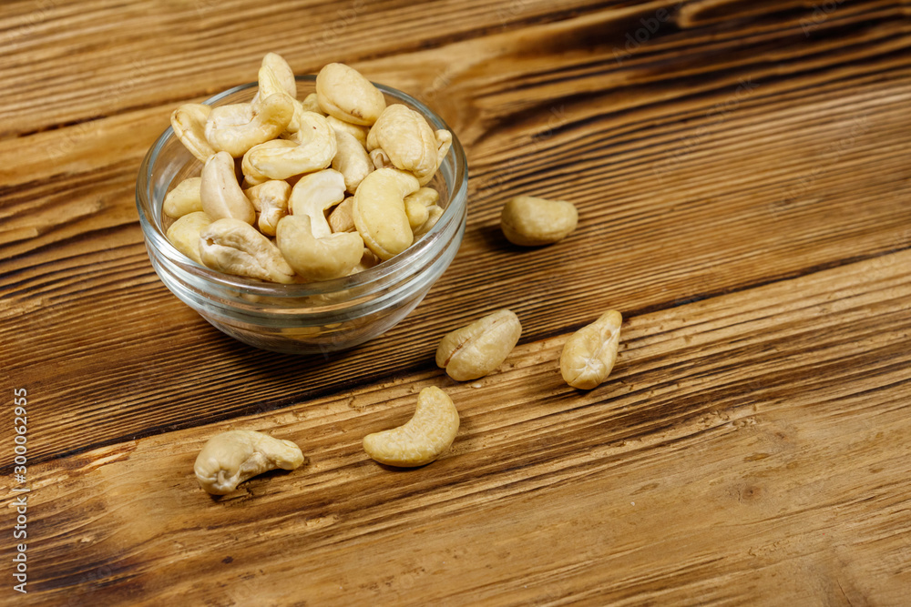 Glass bowl with raw cashew nuts on a wooden table Glass bowl with raw cashew nuts on a wooden table