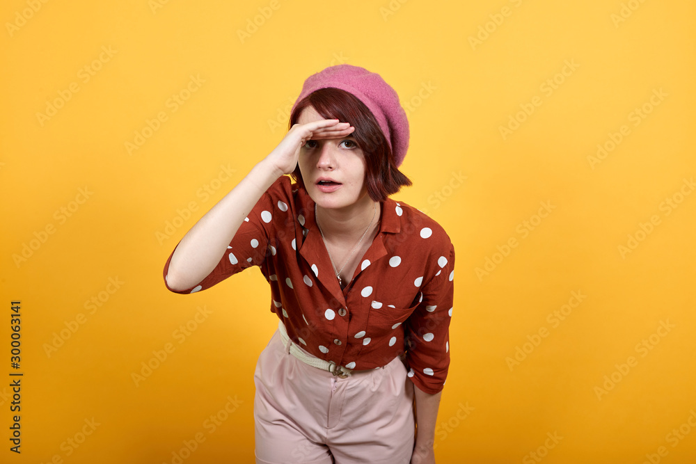 Attractive caucasian young lady wearing red shirt over isolated yellow background happy and smiling looking far away with hand over head. Searching concept Attractive caucasian young lady wearing red shirt over isolated yellow background happy and smiling looking far away with hand over head. Searching concept