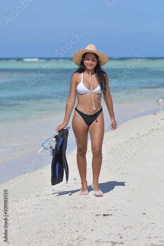 Young Girl wwalking on summer tropical beach island with snorkeling mask and fins on the white sand beach wearing Bikini 