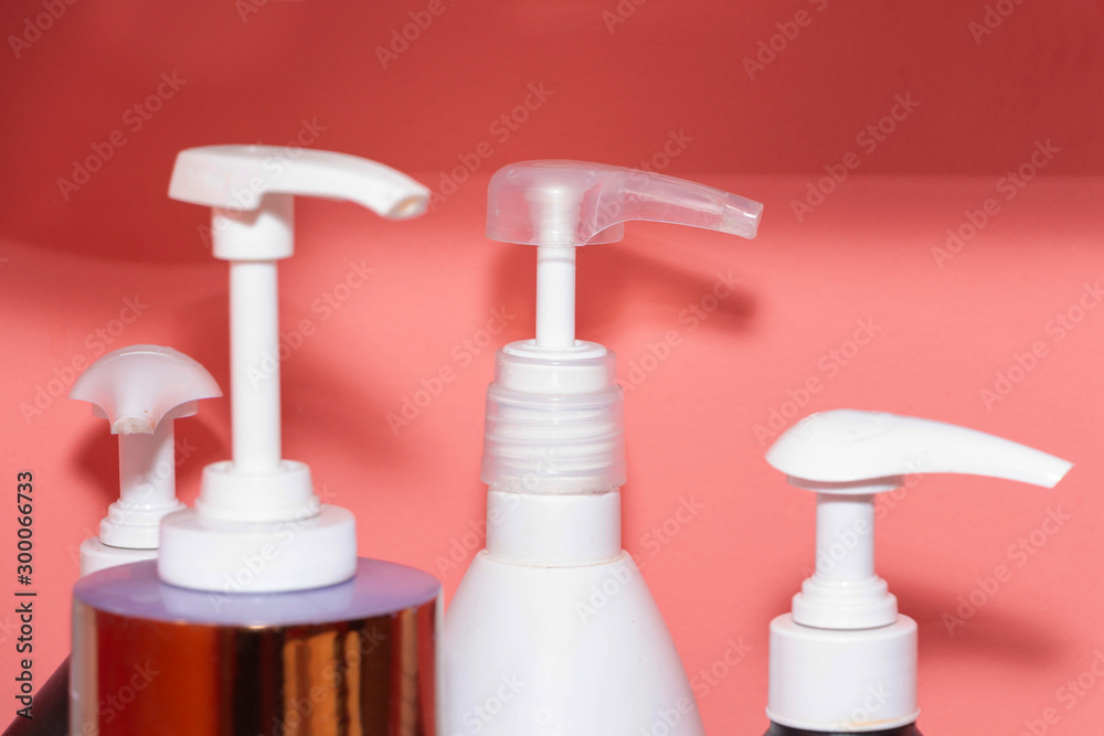 Three bottles of shampoo or shower gel, cream dispenser on colored background with copy space. Three bottles of shampoo or shower gel, cream dispenser on colored background with copy space.
