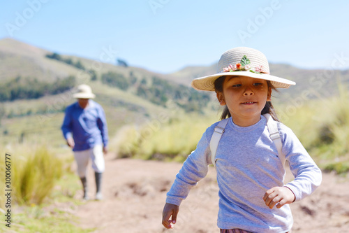 Little latin girl with backpack running in the countryside.