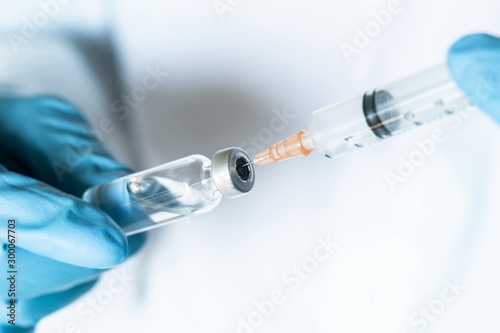Doctor or nurse hand in blue gloves holding flu and measles vaccine vial and syringe for baby vaccination, medicine and drug concept photo