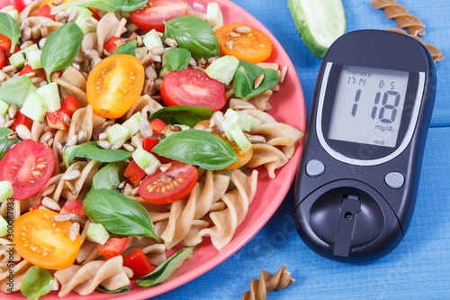 Glucose meter for checking sugar level and fresh salad with wholegrain pasta and vegetables. Best food for diabetics